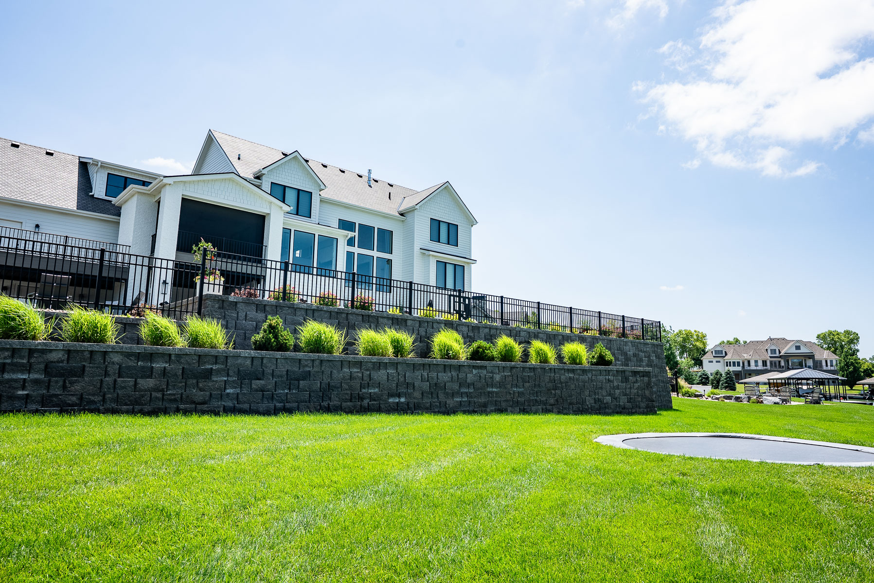 trampoline stone retaining walls ornamental grasses lawn backyard