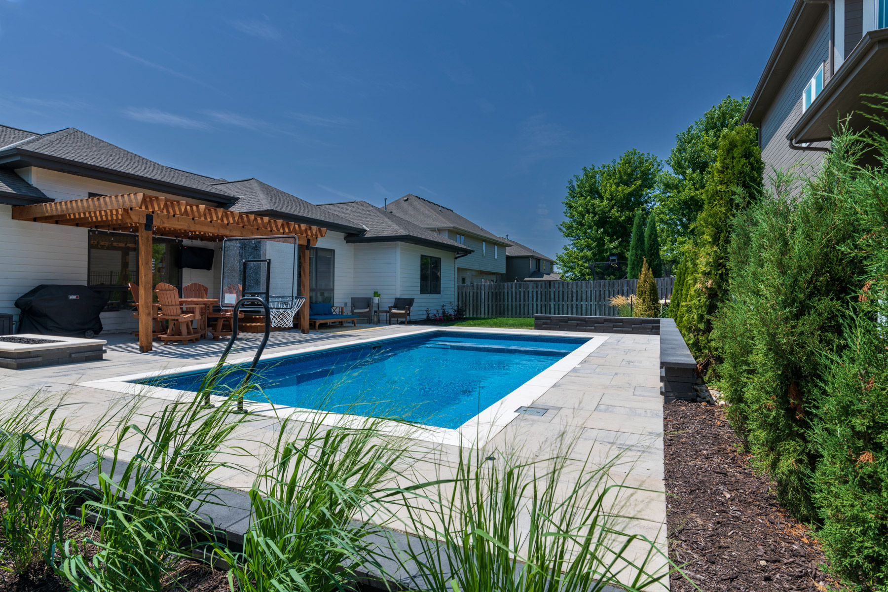 stone pool deck wood pergola retaining wall arborvitae firepit seating hoop